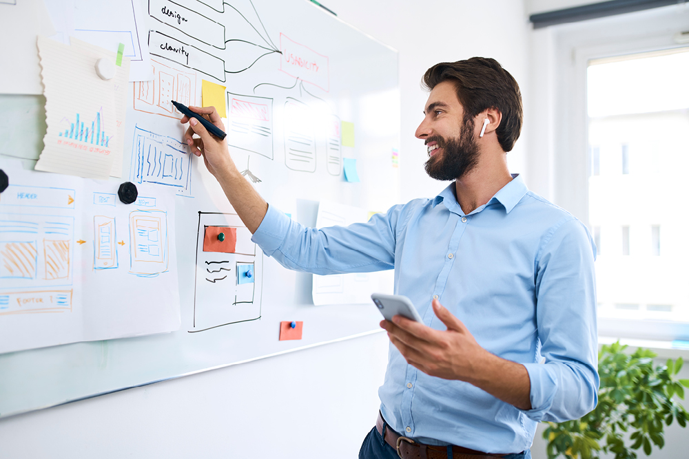 How consistent brand messaging moves you beyond the dollar value. Caucasian man with beard wearing a blue shirt and smiling whilst working on laptop.